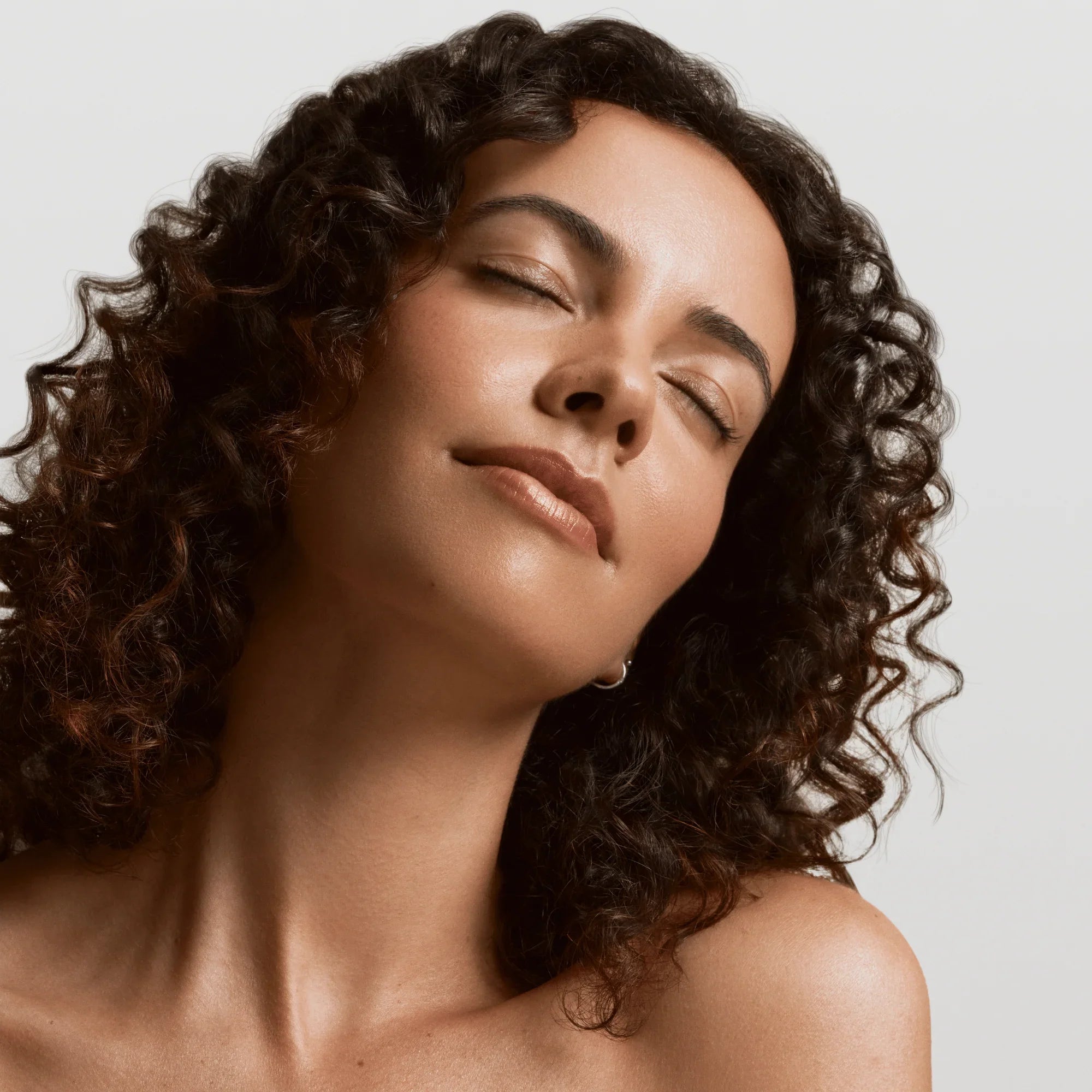 Femme aux cheveux bouclés avec une peau éclatante et lumineuse.